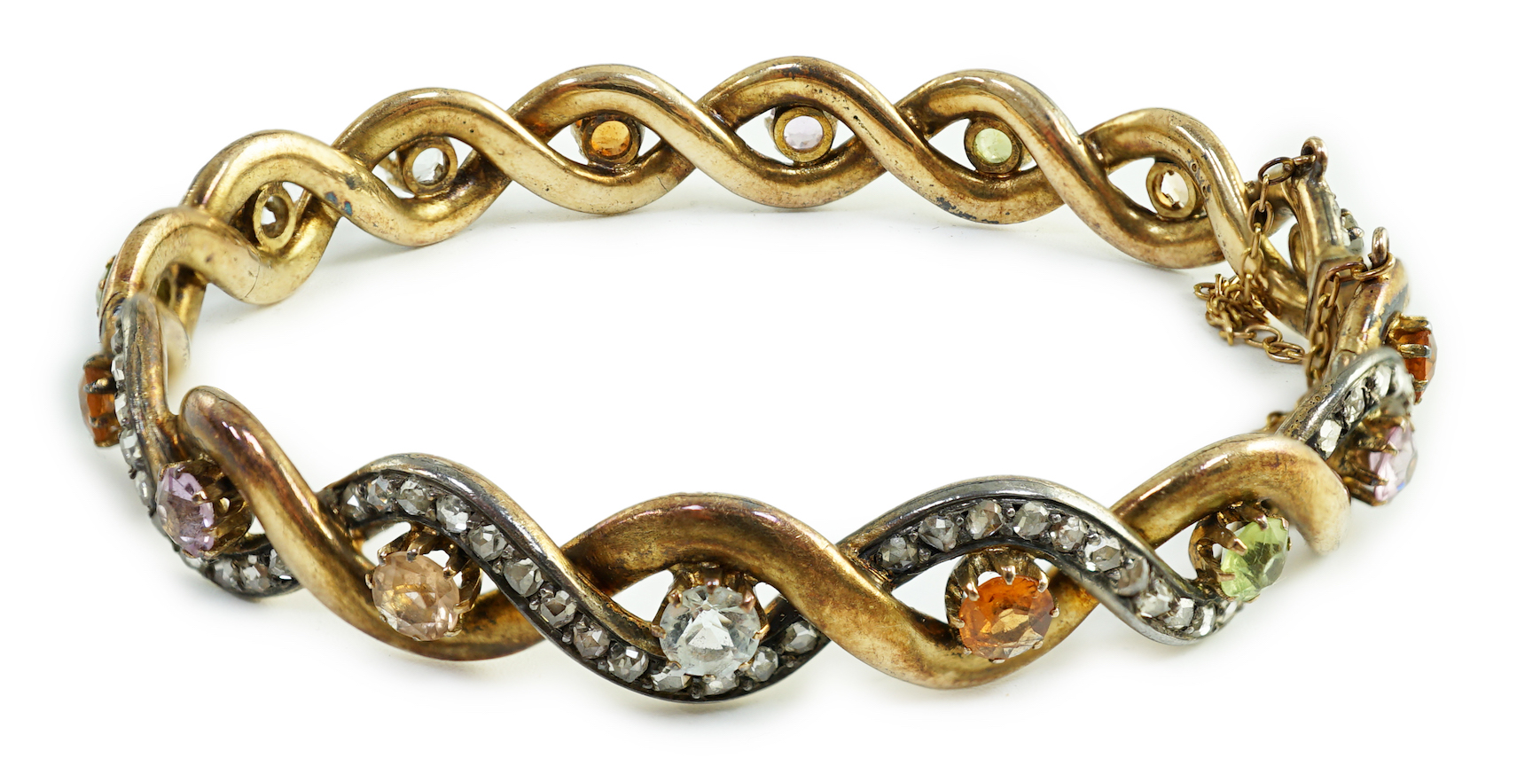 A late 19th/early 20th century French 18ct gold and silver rose cut diamond and multi gem set spiral hinged bangle